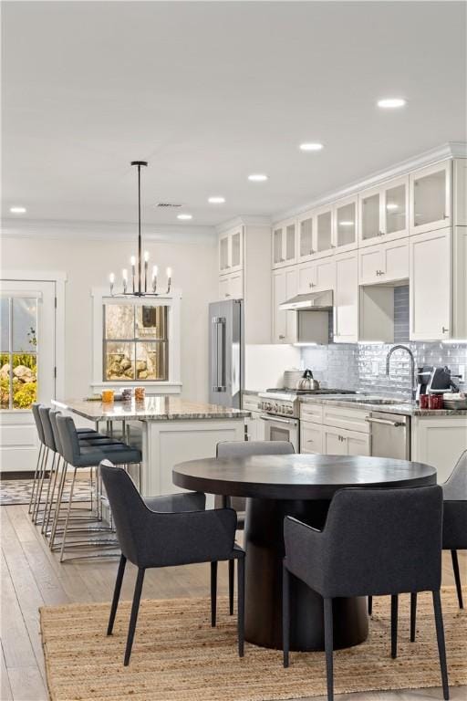 kitchen with white cabinetry, high quality appliances, a kitchen breakfast bar, and a kitchen island