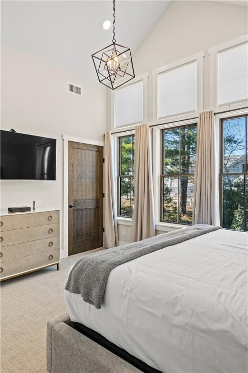 carpeted bedroom featuring a chandelier and high vaulted ceiling