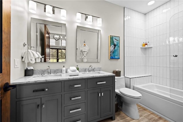 full bathroom featuring tiled shower / bath combo, vanity, wood-type flooring, and toilet