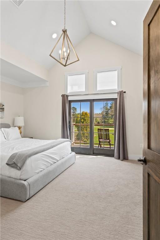 carpeted bedroom with access to exterior, high vaulted ceiling, and a notable chandelier