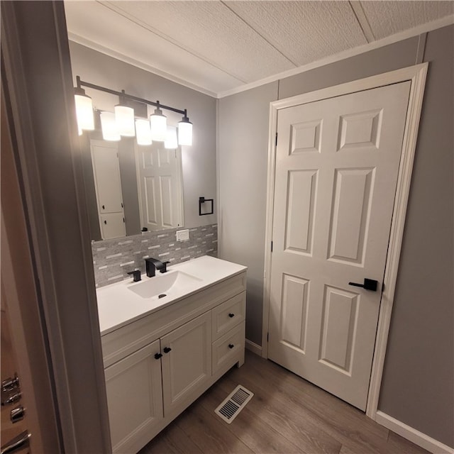 bathroom featuring tasteful backsplash, wood-type flooring, vanity, and a textured ceiling