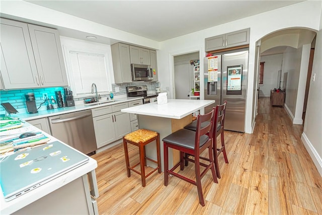 kitchen featuring light wood-type flooring, sink, a kitchen island, and appliances with stainless steel finishes