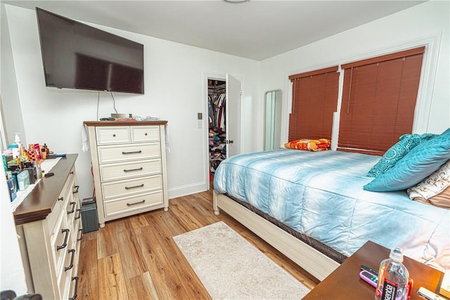 bedroom with a spacious closet and light wood-type flooring