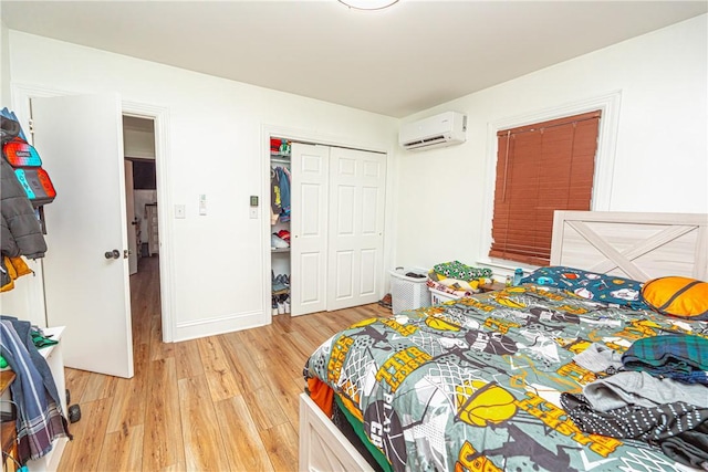 bedroom featuring a closet, an AC wall unit, and light hardwood / wood-style flooring