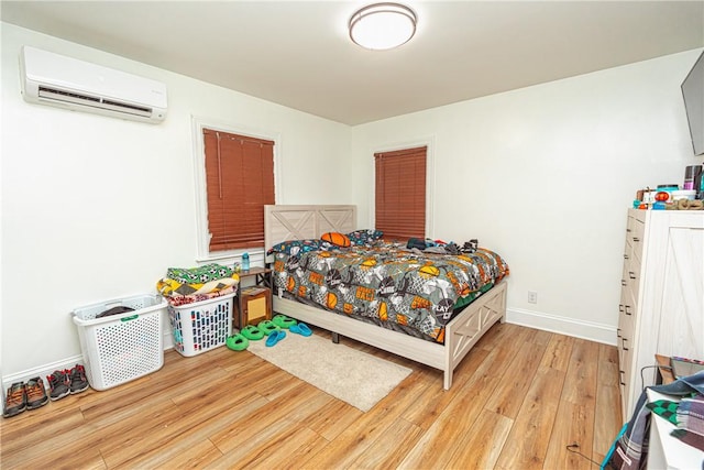 bedroom with light hardwood / wood-style floors and a wall unit AC