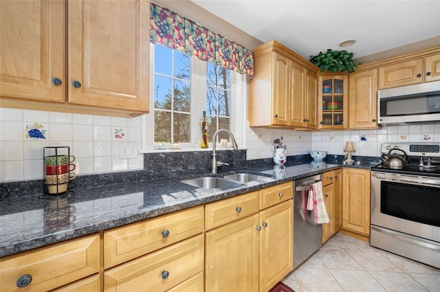 kitchen featuring sink, backsplash, stainless steel appliances, and dark stone counters