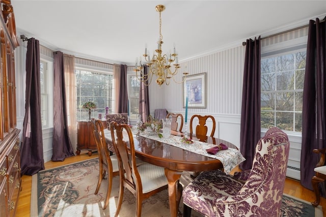 dining area with an inviting chandelier, a baseboard heating unit, light hardwood / wood-style flooring, and ornamental molding