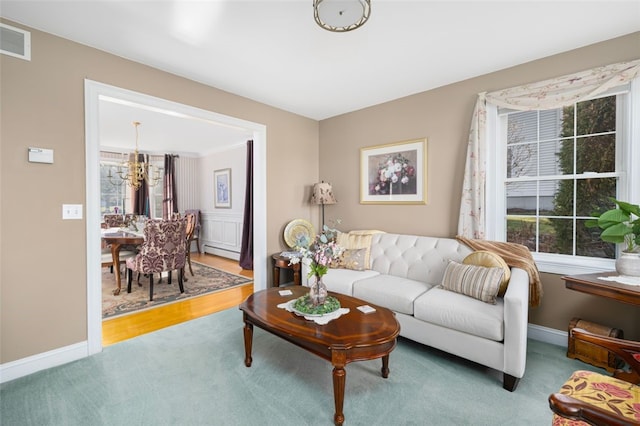 carpeted living room with a baseboard radiator and an inviting chandelier