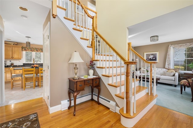 stairway with a baseboard heating unit and hardwood / wood-style flooring