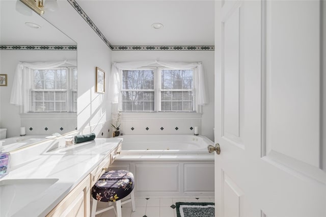 bathroom featuring tile patterned flooring, vanity, a healthy amount of sunlight, and a bath