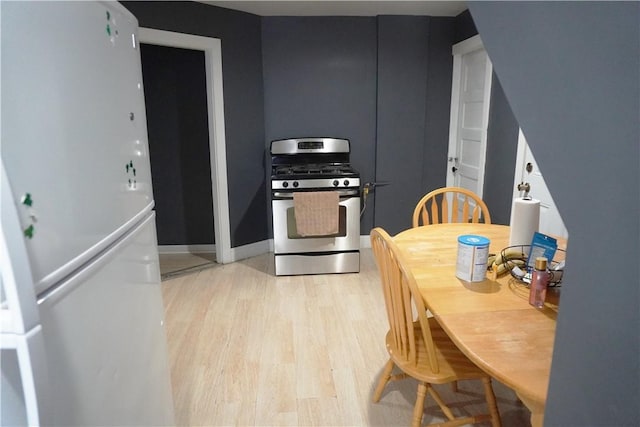 kitchen with stainless steel gas range oven, light hardwood / wood-style floors, and white refrigerator