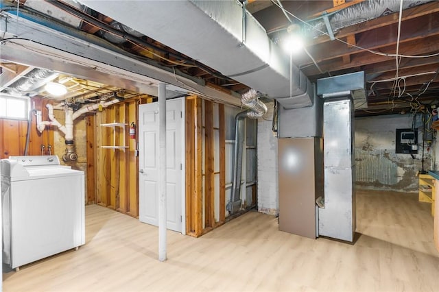 basement featuring washer / dryer, heating unit, and light wood-type flooring