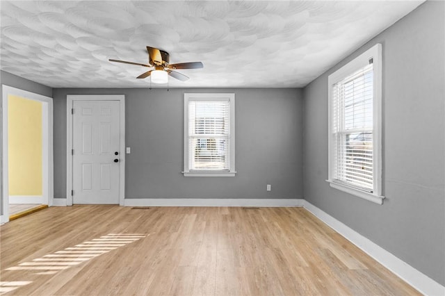 empty room featuring ceiling fan, light hardwood / wood-style flooring, and a textured ceiling