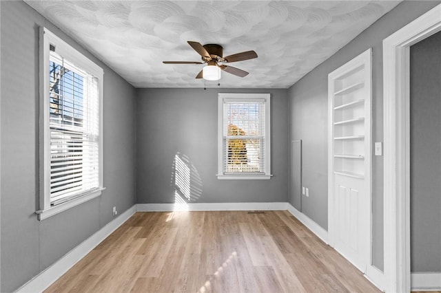 spare room featuring ceiling fan, built in features, and light hardwood / wood-style flooring