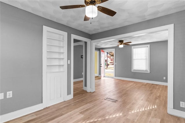 unfurnished room featuring built in shelves and light hardwood / wood-style flooring