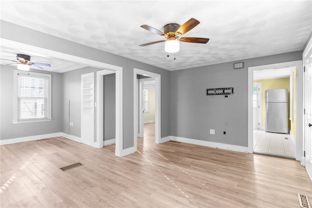 unfurnished room featuring a textured ceiling, light hardwood / wood-style flooring, and ceiling fan