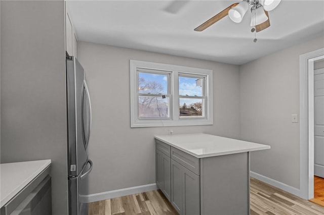 kitchen featuring gray cabinets, stainless steel refrigerator, ceiling fan, light hardwood / wood-style floors, and kitchen peninsula