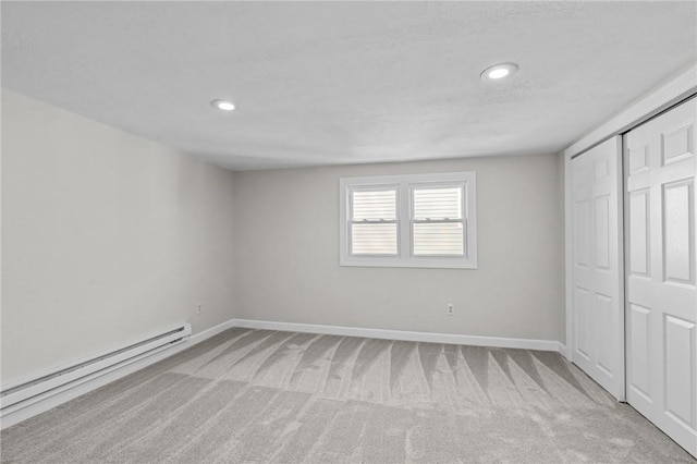 unfurnished bedroom with light carpet, baseboard heating, and a closet