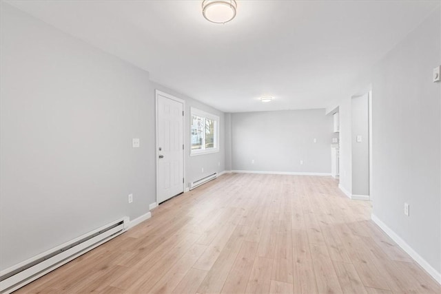 unfurnished room with a baseboard heating unit and light hardwood / wood-style floors