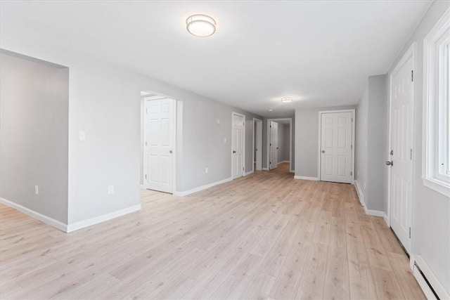 empty room featuring a baseboard radiator and light hardwood / wood-style floors