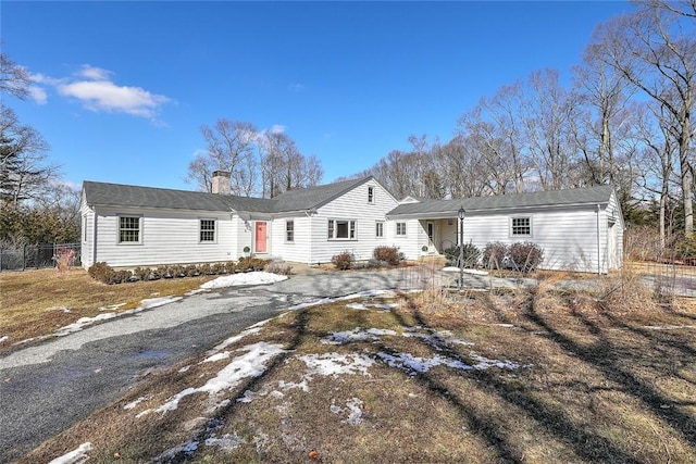 ranch-style home with driveway, a chimney, and fence