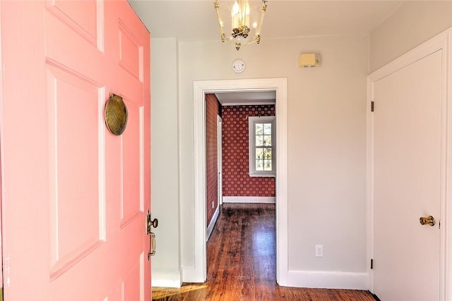 interior space featuring a notable chandelier, dark wood finished floors, baseboards, and wallpapered walls