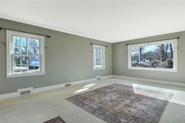 carpeted spare room with visible vents and baseboards