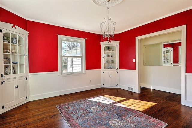 unfurnished dining area featuring a chandelier, wood finished floors, visible vents, baseboards, and ornamental molding