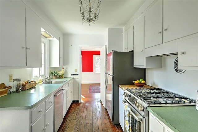 kitchen featuring dark wood-style flooring, stainless steel appliances, light countertops, white cabinets, and a sink