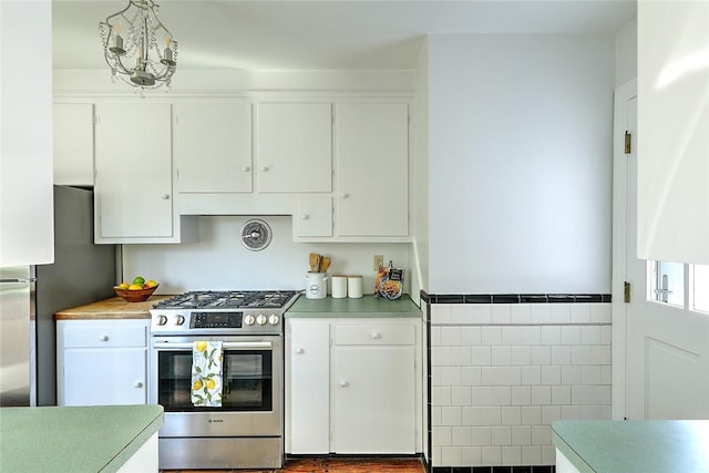 kitchen featuring stainless steel appliances, light countertops, white cabinetry, and tile walls