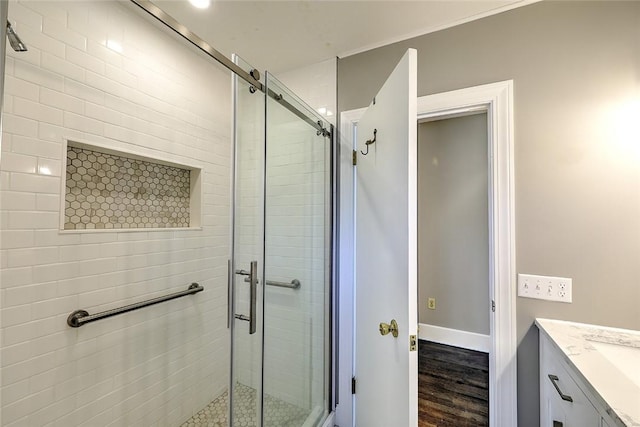 bathroom with wood finished floors, a shower stall, vanity, and baseboards