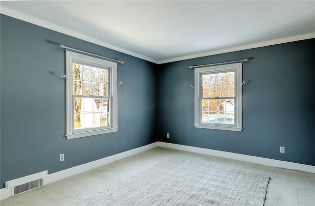 carpeted empty room with baseboards, visible vents, and crown molding