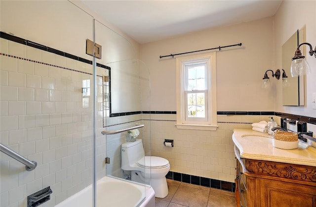 bathroom featuring toilet, a wainscoted wall, tile patterned flooring, vanity, and tile walls