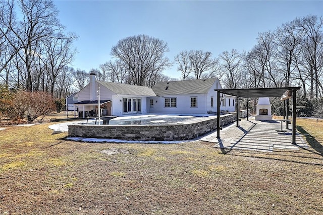 back of property with driveway, a patio area, exterior fireplace, and a carport