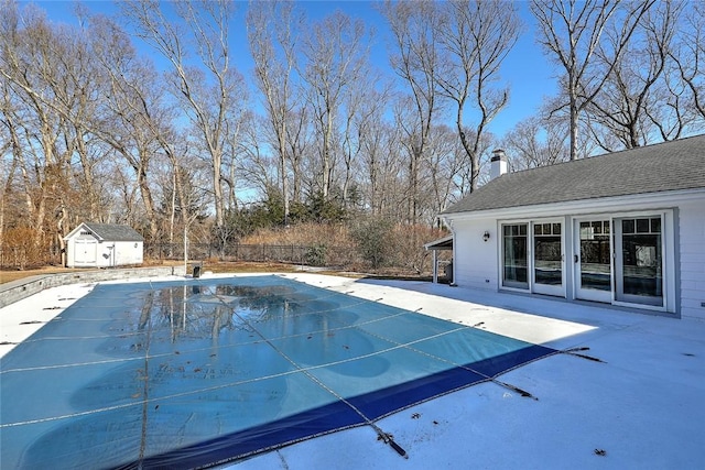 view of pool featuring a patio, an outdoor structure, fence, a fenced in pool, and a shed