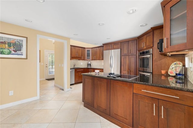 kitchen with light tile patterned flooring, sink, dark stone countertops, backsplash, and stainless steel appliances