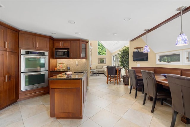 kitchen with vaulted ceiling, double oven, built in microwave, dark stone counters, and hanging light fixtures