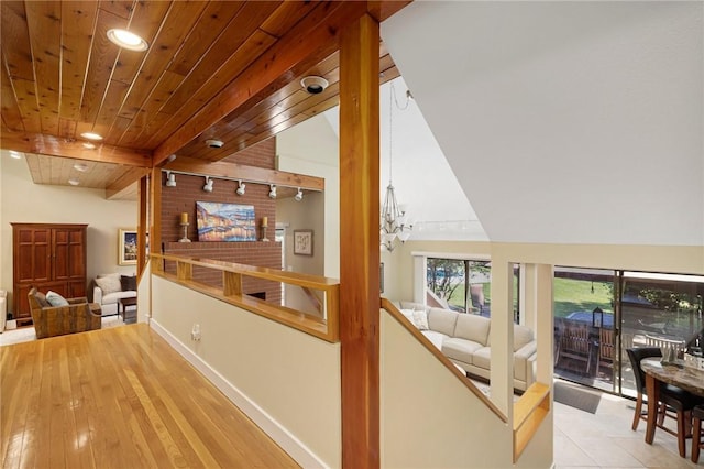 hallway featuring wood ceiling, track lighting, a chandelier, and vaulted ceiling