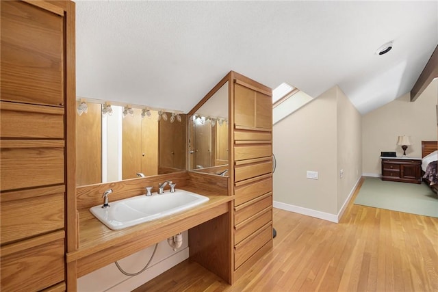 bathroom featuring lofted ceiling, sink, and wood-type flooring