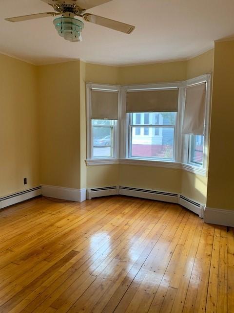 unfurnished room featuring a baseboard heating unit, light hardwood / wood-style flooring, and ceiling fan