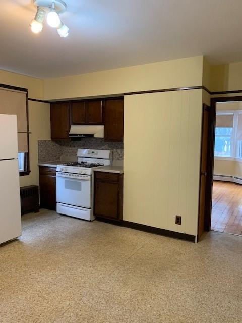 kitchen with tasteful backsplash, white appliances, dark brown cabinets, and baseboard heating