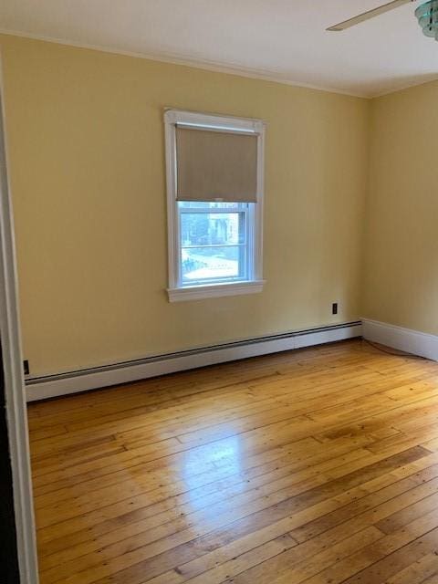 empty room featuring light hardwood / wood-style flooring, a baseboard radiator, and ceiling fan