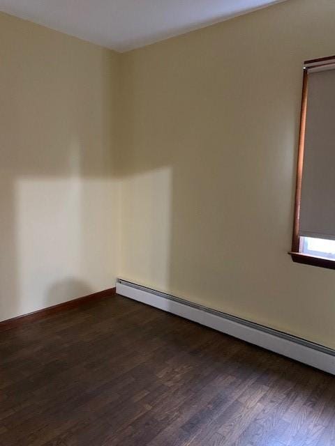 empty room with dark hardwood / wood-style flooring and baseboard heating