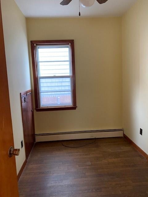 empty room with ceiling fan, a baseboard heating unit, and dark hardwood / wood-style flooring