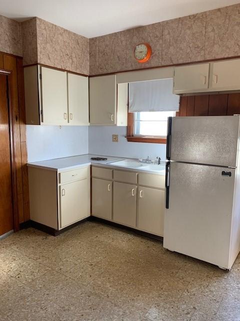 kitchen featuring white refrigerator, sink, and white cabinets