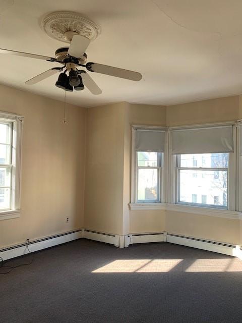 spare room with ceiling fan and dark carpet