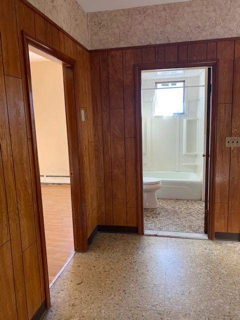 corridor with wooden walls and a baseboard heating unit