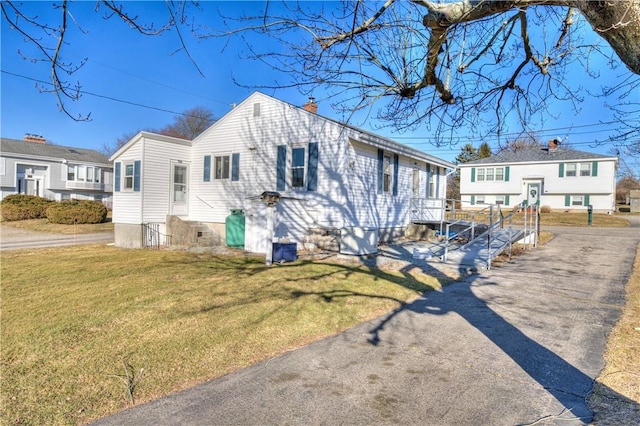 view of front of home with entry steps, a front lawn, a chimney, and a residential view