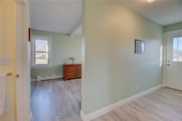 interior space with a baseboard heating unit, baseboards, wood finished floors, and a healthy amount of sunlight