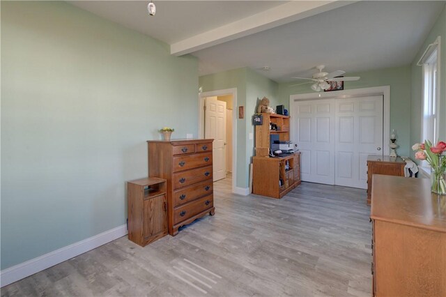 bedroom featuring beamed ceiling, light hardwood / wood-style flooring, and a closet